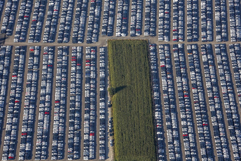 Storage area for new cars next to a cornfield