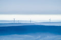 Dunstige Landschaft mit Windrädern und Funkmast