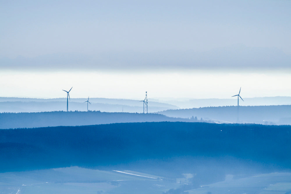 Dunstige Landschaft mit Windrädern und Funkmast