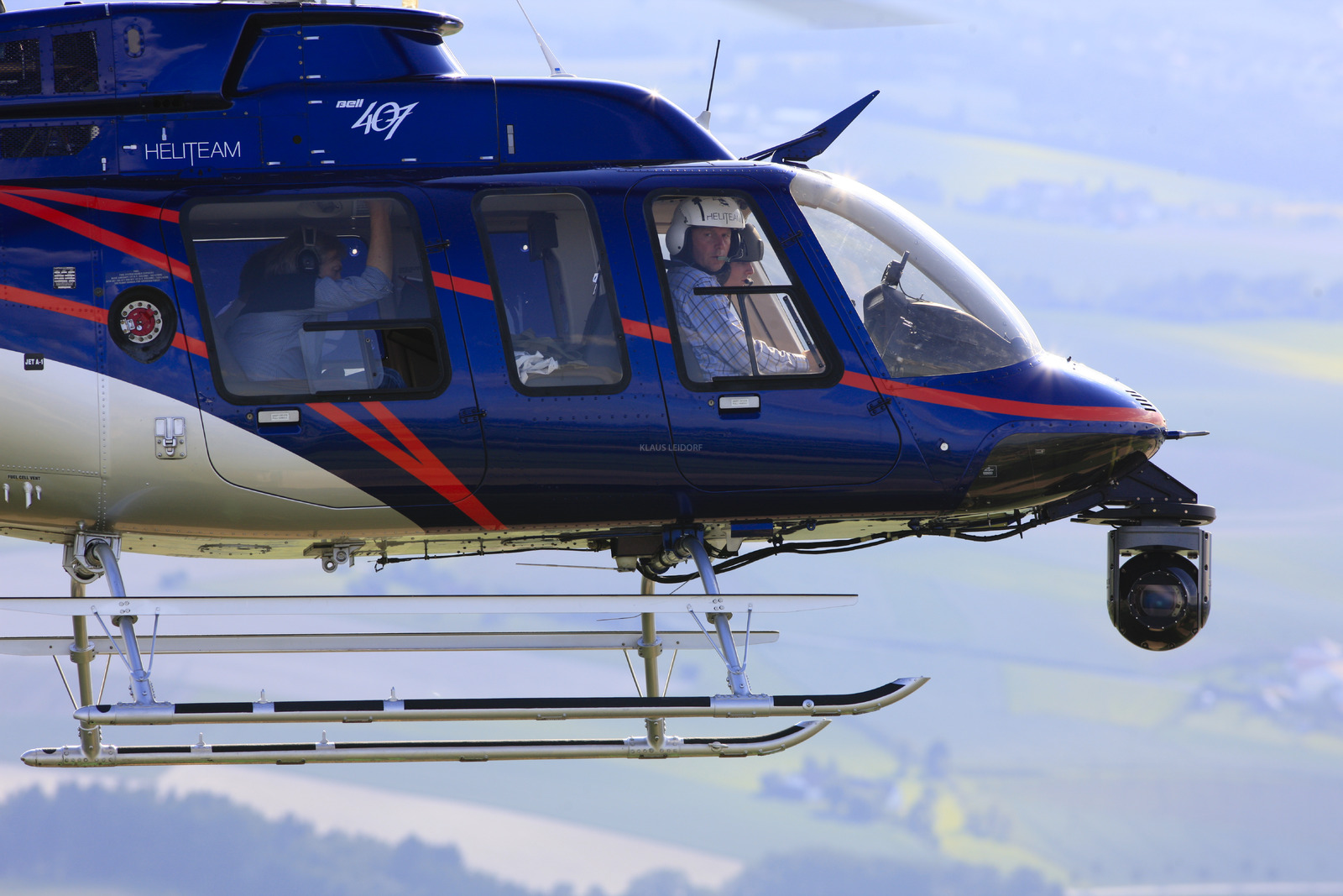 Luftaufnahme von einem Hubschrauber Bell 407 mit einer Cineflex-Filmkamera bei der Arbeit